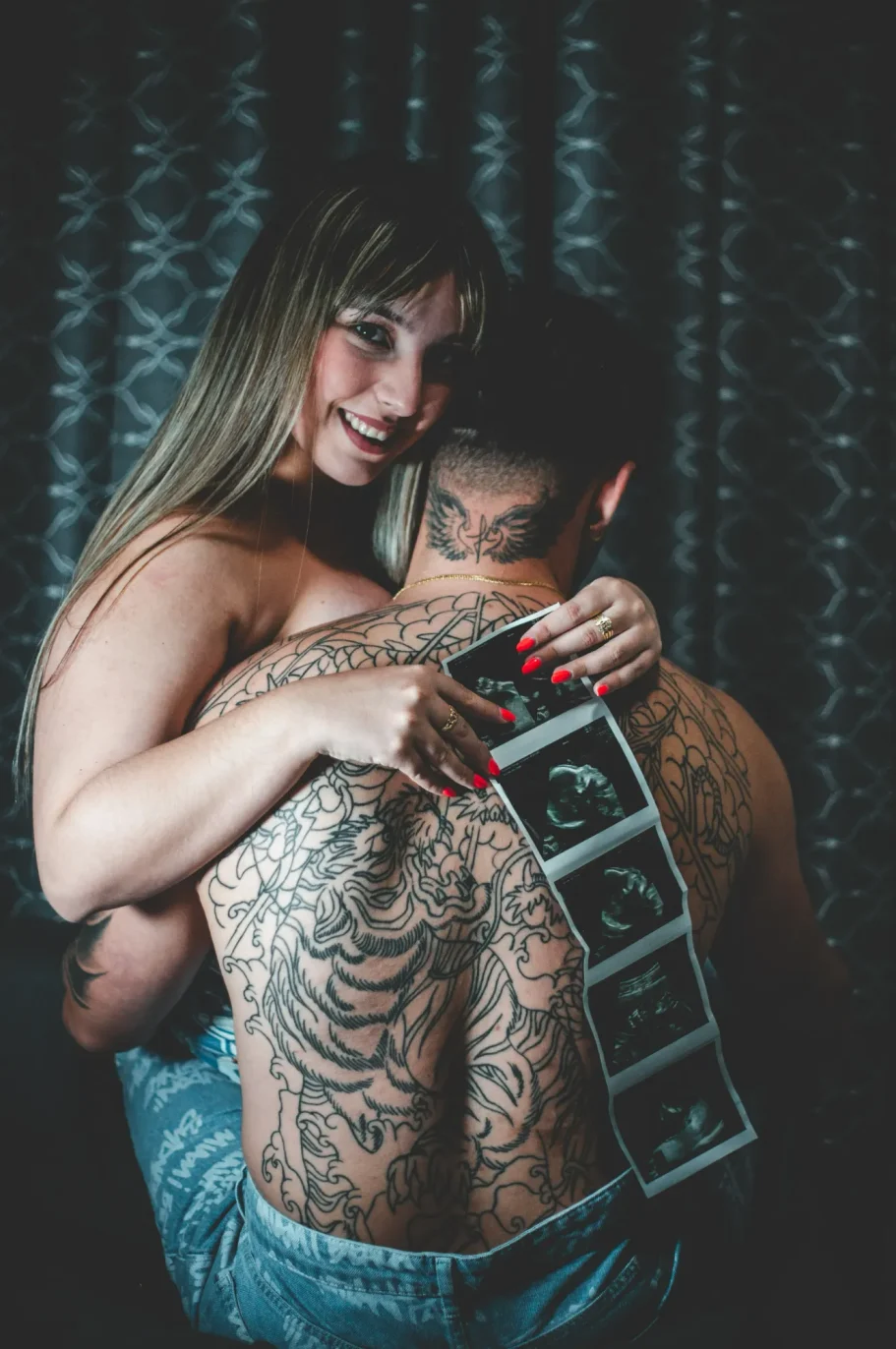 Foto de pareja de padres. Mamá embarazada abrazando a papá y sosteniendo una ecografía de bebé