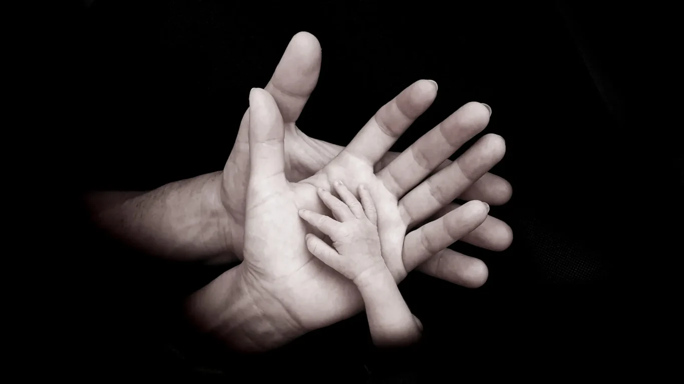 Detalle de manos de recién nacido sujetando el dedo de sus padres en Tenerife