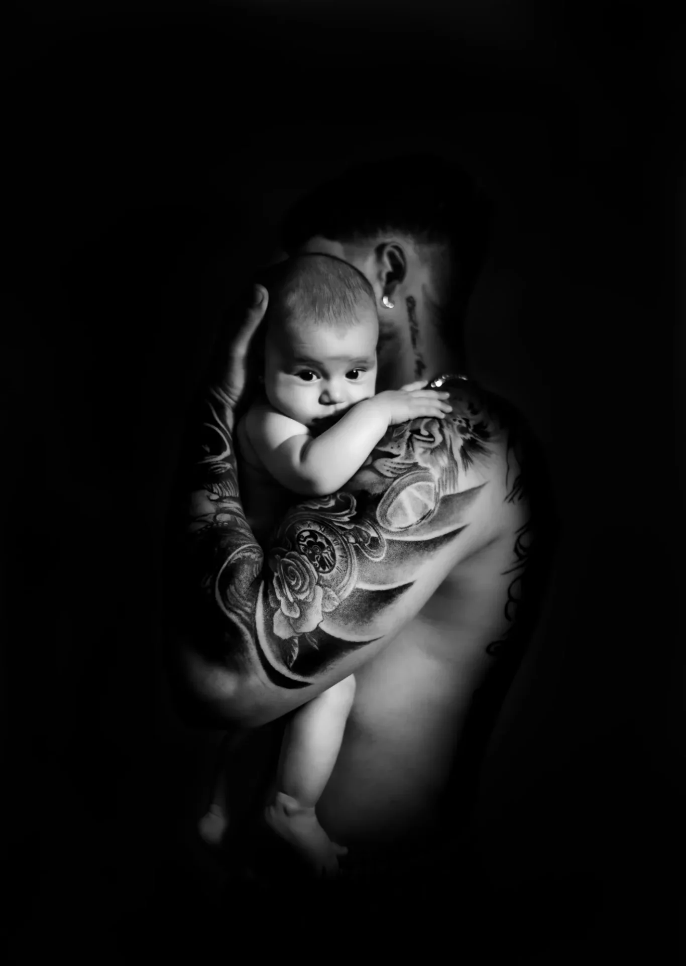 Retrato artístico de recién nacido abrazado por su papá con luz suave en Tenerife.